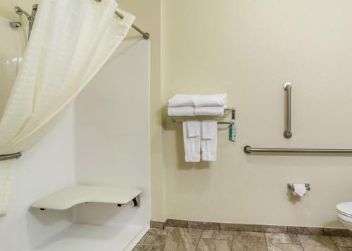 een badkamer met een douche, een toilet en handdoeken bij Cobblestone Hotel & Suites - Andrews in Andrews