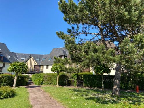 a house with a tree in the yard at Escapade à Cabourg, 300M plage, calme et chaleureux in Cabourg