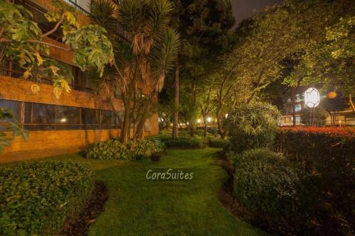 un giardino con alberi e cespugli di fronte a un edificio di Cora 127 Plenitud a Bogotá