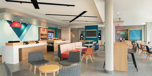 a lobby with chairs and tables and a cafeteria at avid hotel - Madison - Huntsville West by IHG in Madison
