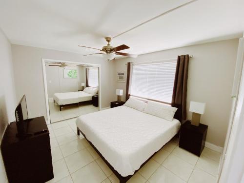 a bedroom with a white bed and a mirror at The Jasmine Apartments in Fort Lauderdale