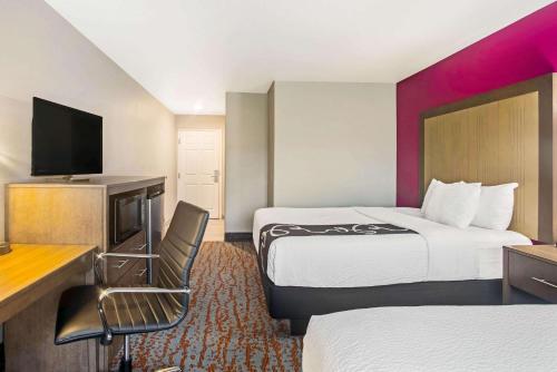 a hotel room with two beds and a flat screen tv at La Quinta by Wyndham Fort Smith in Massard