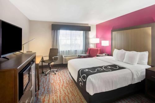 a hotel room with a bed and a flat screen tv at La Quinta by Wyndham Fort Smith in Massard