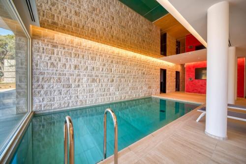a pool in a house with a brick wall at Villa Solaria in Sveti Stefan