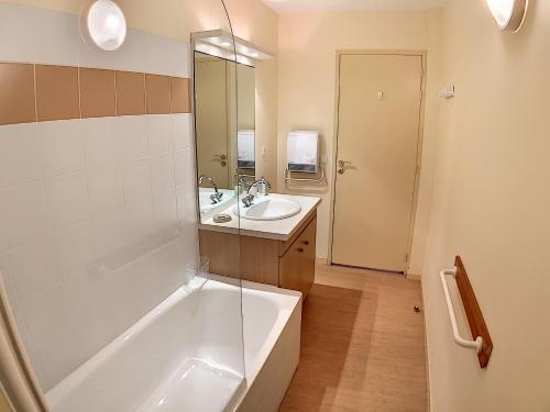 uma casa de banho com uma banheira e um lavatório e uma banheira em Appartement 208 Résidence du Grand Hotel Aulus-les-Bains em Aulus-les-Bains