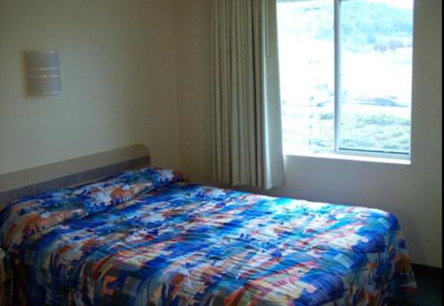 a bedroom with a bed with a colorful comforter and a window at Motel 6-Roseburg, OR in Roseburg