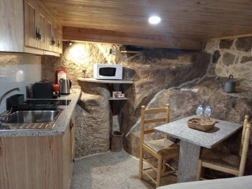 a kitchen with a sink and a table with a microwave at Casas da Villa- Monsanto in Monsanto