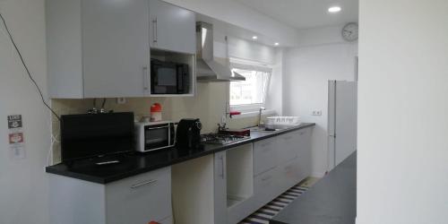 a kitchen with white cabinets and a black counter top at GuestHouse Marialva Park in Corroios