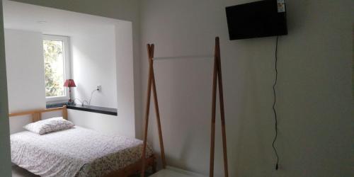 a bedroom with a bed and a television on the wall at GuestHouse Marialva Park in Corroios