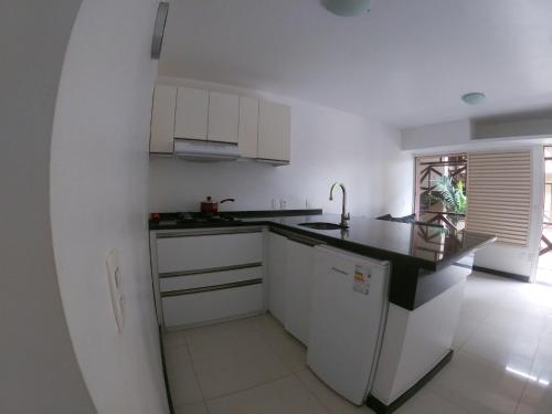 une cuisine avec des placards blancs et un comptoir noir dans l'établissement ECO PARADISE _ CUMBUCO BOUTIQUE, à Cumbuco