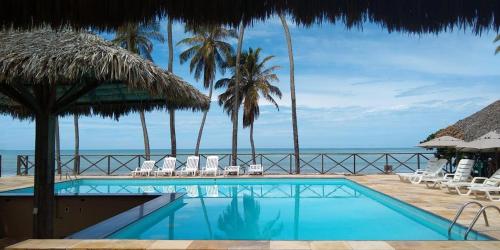 a swimming pool with chairs and the ocean in the background at ECO PARADISE _ CUMBUCO BOUTIQUE in Cumbuco