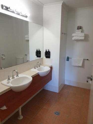 baño con 2 lavabos y espejo grande en Ramada Encore Belconnen, en Canberra