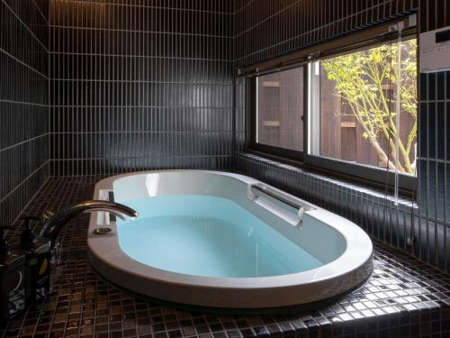 y baño con bañera y ventana. en Gion Shirakawa Kouki Machiya House, en Kioto