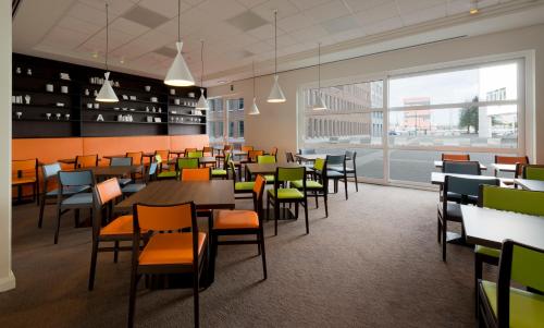 uma cafetaria com mesas e cadeiras e uma grande janela em Holiday Inn Express Antwerpen City North by IHG em Antuérpia