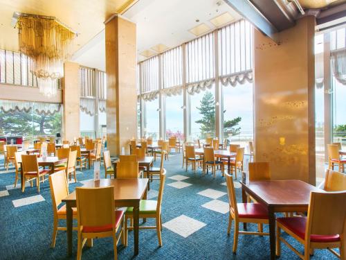 comedor con mesas y sillas y ventanas grandes en Diamond Setouchi Marine Hotel, en Tamano