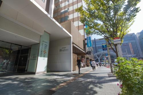 a person walking down a sidewalk next to a building at JR Kyushu Hotel Blossom Hakata Central in Fukuoka