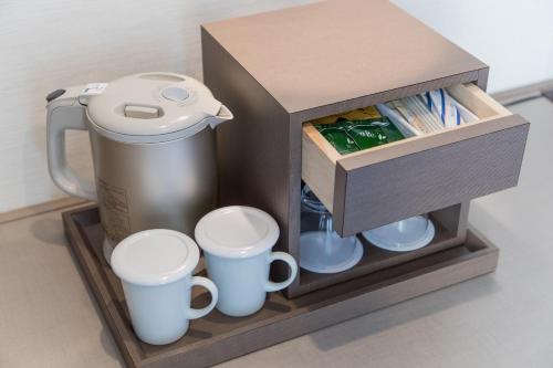 a coffee maker and cups on a wooden stand at JR Kyushu Hotel Blossom Hakata Central in Fukuoka