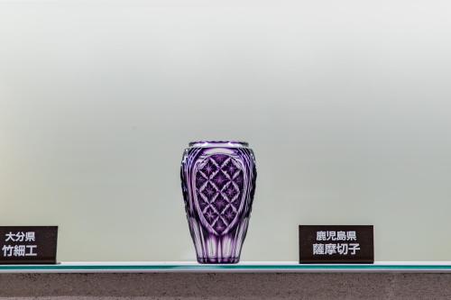 a purple glass vase on a shelf with three candles at JR Kyushu Hotel Blossom Hakata Central in Fukuoka