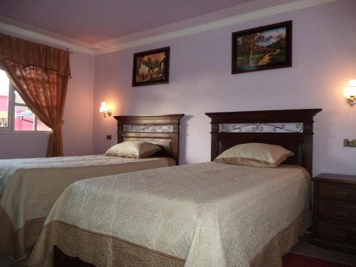 a bedroom with two beds and two pictures on the wall at Apart Hotel Turquesa in Potosí