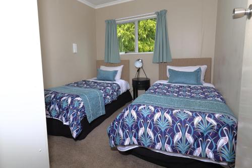 a bedroom with two beds and a window at Aden Motel in Te Anau