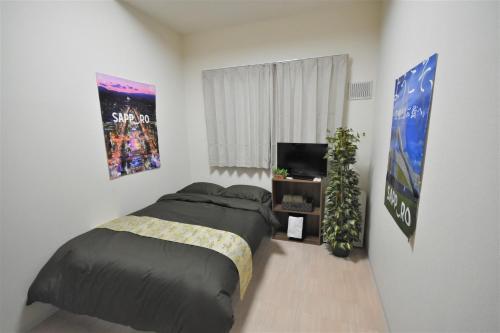 a bedroom with a bed and a flat screen tv at KIYAZA Road Sapporo in Sapporo