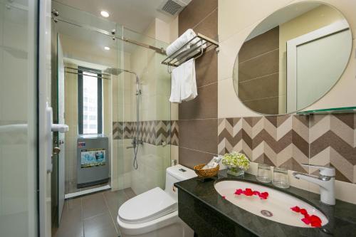 a bathroom with a sink and a toilet and a mirror at Sea Swan Apartment and Hotel in Da Nang