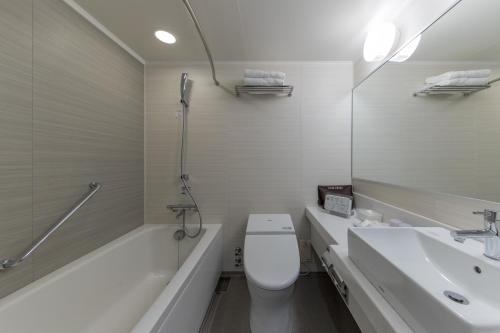 a bathroom with a toilet and a sink and a mirror at JR Kyushu Hotel Blossom Hakata Central in Fukuoka