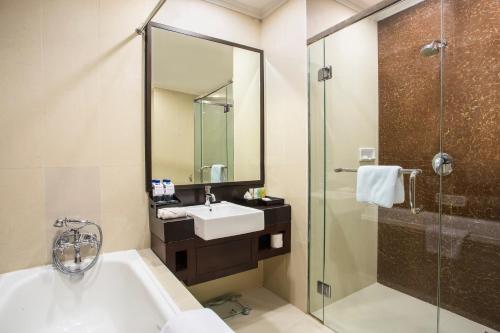 a bathroom with a tub and a sink and a shower at Swiss-Belhotel Merauke in Merauke