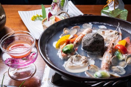 a pan of food with oysters and vegetables on a table at Hakuunsou in Yugawara