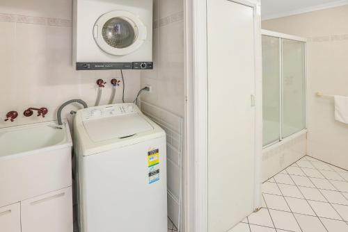 a bathroom with a sink and a washing machine at Koala Court Holiday Apartments in Cairns