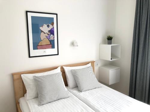 a bed with two pillows and a picture on the wall at Astos Vila in Palanga