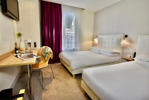 ロリアンにあるHôtel Escale Oceania Lorientのベッド2台とデスクが備わるホテルルームです。