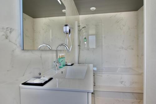 a white bathroom with a sink and a tub at Hôtel Escale Oceania Lorient in Lorient