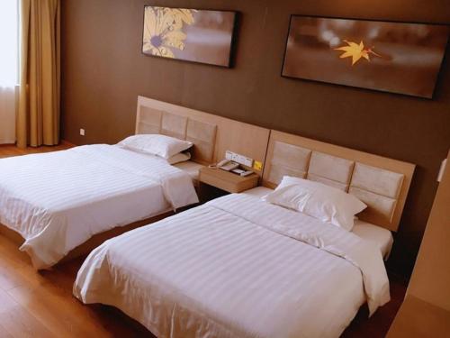 two beds in a hotel room with white sheets at 7Days Inn Yancheng Jianhu Xiu Fu South Road in Yancheng