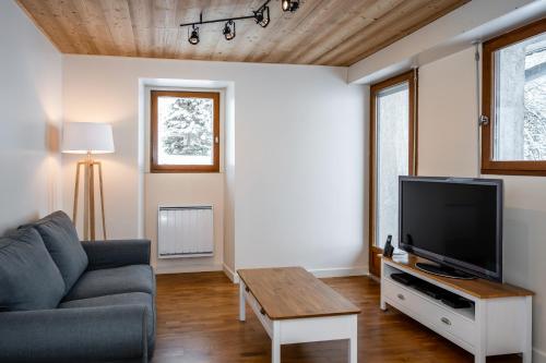 a living room with a couch and a tv at Le Refuge in Lamoura