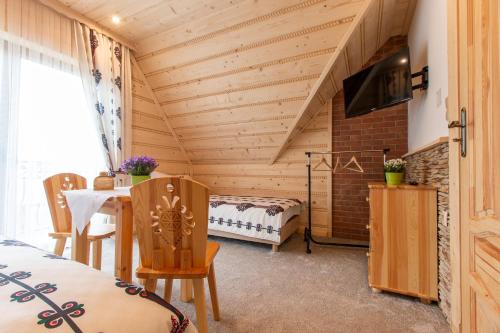 a room with a bed and a table with chairs at Domki Pod Jemiołą in Zakopane