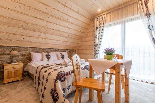 a bedroom with a bed and a table and a window at Domki Pod Jemiołą in Zakopane