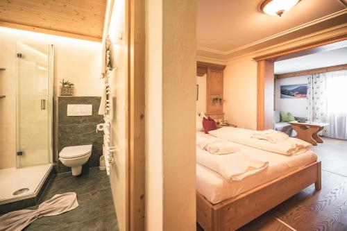 a bedroom with a bed and a bathroom with a shower at Hotel Schartner in Altenmarkt im Pongau