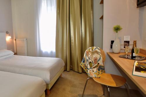 a hotel room with a bed and a desk with a chair at Hôtel Escale Oceania Lorient in Lorient