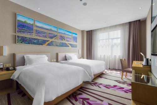 een hotelkamer met 2 bedden en een televisie bij Lavande Hotel Zhaoqing Qixingyan Scenic Spot Yihua International Square in Zhaoqing