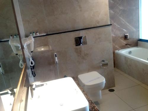 a bathroom with a toilet and a sink and a tub at Hotel Preethi International in Mysore
