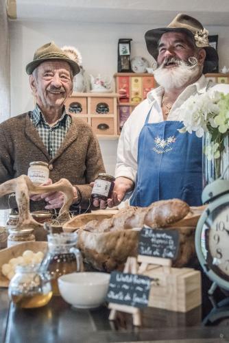 two older men standing behind a table with bread at Hotel Edelweiss in Braies