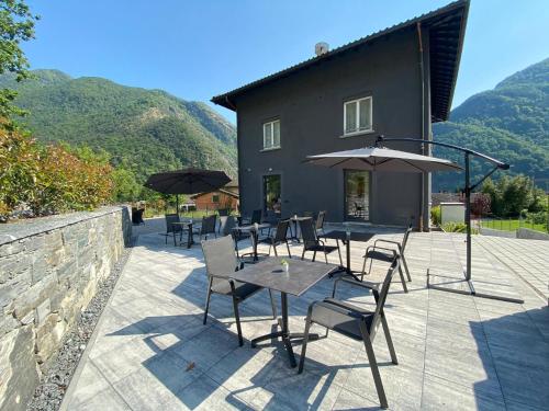 eine Terrasse mit Tischen, Stühlen und Sonnenschirmen in der Unterkunft B&B Cà Nosa in Gordevio