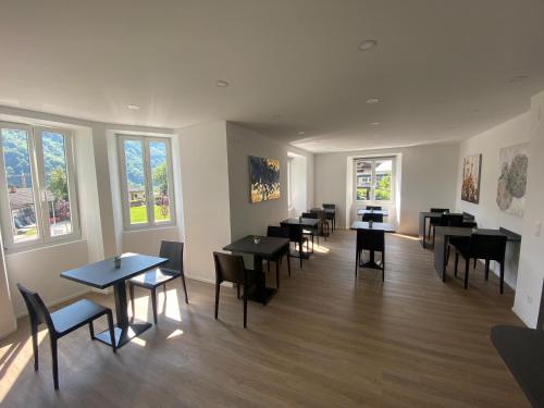a dining room with tables and chairs and windows at B&B Cà Nosa in Gordevio