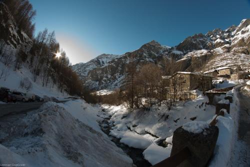 a snow covered mountain with a river in the foreground at Chalet Della Guida in Bardonecchia