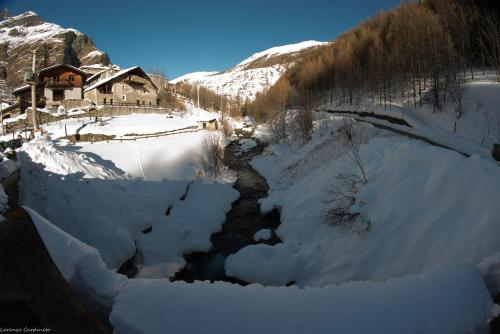 a river covered in snow in front of a house at Chalet Della Guida in Bardonecchia