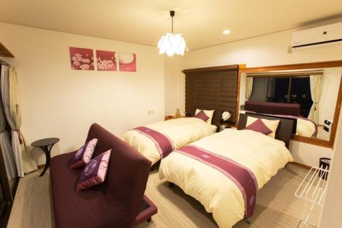 a hotel room with two beds and a couch at 熱海の海が一望できる温泉付貸別荘 満月あじろ mitsukiajiro in Atami