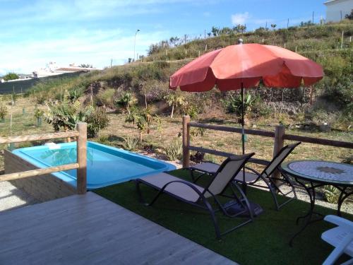 a patio with two chairs and an umbrella next to a pool at Paraíso de Torrox Costa in Torrox Costa