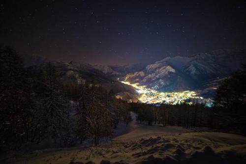 a view of a city at night with snow covered mountains at Chalet Della Guida in Bardonecchia
