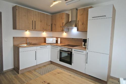 a kitchen with white cabinets and a white refrigerator at Ferienwohnung "Haus Falle" in Schiefling am See